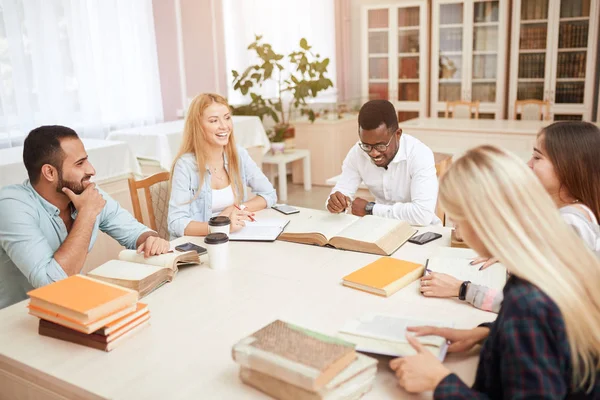 Grupo de personas multirraciales que estudian con libros en la biblioteca universitaria . — Foto de Stock