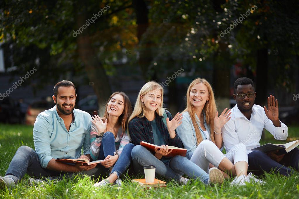 Grupo mixto de estudiantes sentados juntos en el césped verde del