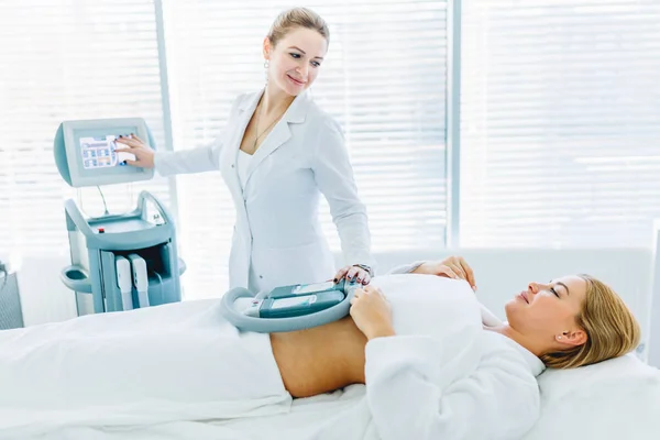 Mladá žena ležící v lékařské lehátko s chladící prvky na břicho v klinice — Stock fotografie
