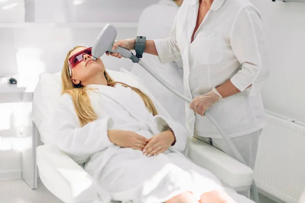 Woman getting laser and ultrasound face treatment in medical spa center