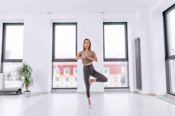 Mujer de yoga de pie sobre una pierna en posición de yoga — Foto de Stock
