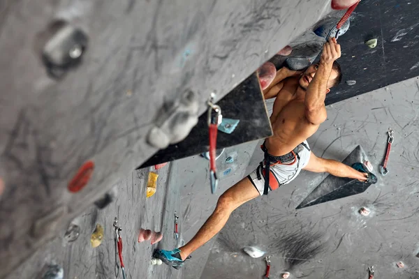 Mężczyzna profesjonalny wspinaczka w kryty trening w bouldering centrum. — Zdjęcie stockowe