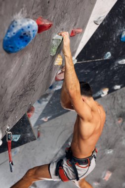 Erkek profesyonel dağcı, kayalık merkezde kapalı alanda çalışıyor..