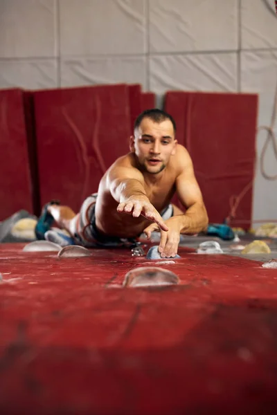 Panorama skott av ung muskulös man träning i inomhus clymbing gym. — Stockfoto