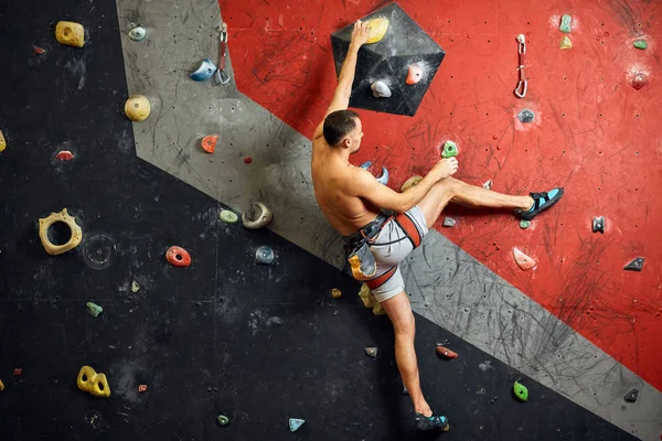 Escalador profissional masculino no treino indoor no centro de pedregulhos . — Fotografia de Stock