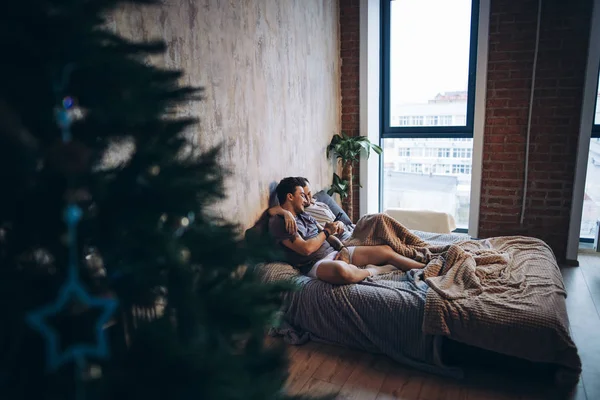 Two attractive gay men spending time together in bedroom with christmas tree.