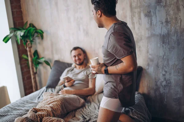 Perfect morning begins with lover and coffee in bed. Two guys resting in bed.