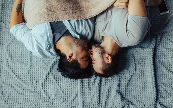 Όμορφος νυσταγμένος άντρας με τρίχες που φιλάει καληνυχτούδια άντρα ξαπλωμένο στο κρεβάτι. — Φωτογραφία Αρχείου
