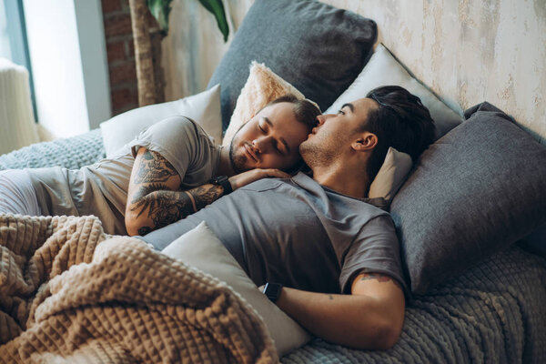 A homosexual couple on bed in studio with loft interior