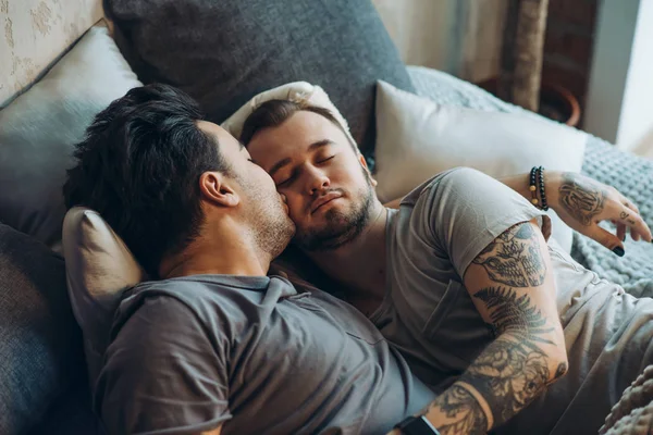 Homosexuální pár na posteli ve studiu s podkrovním interiérem — Stock fotografie
