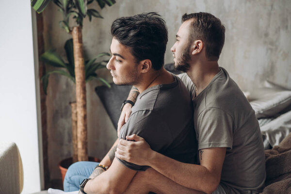 Two sexy caucasian gay guys hugging and having fun in bed indoors