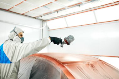 Koruyucu iş kıyafetleri ve solunum cihazında boyacı. Boya odasında araba boyacısı.