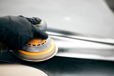 Tamirci boya için araba parçalarını öğütüyor. Araba kaportası kazadan sonra boyayı tamir eder.