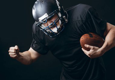 Amerikan futbolu sporcusu siyah stüdyo duvarından izole edildi.