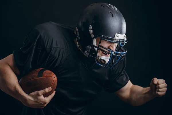 Jugador de fútbol americano deportista en acción aislado sobre la pared de estudio negro —  Fotos de Stock