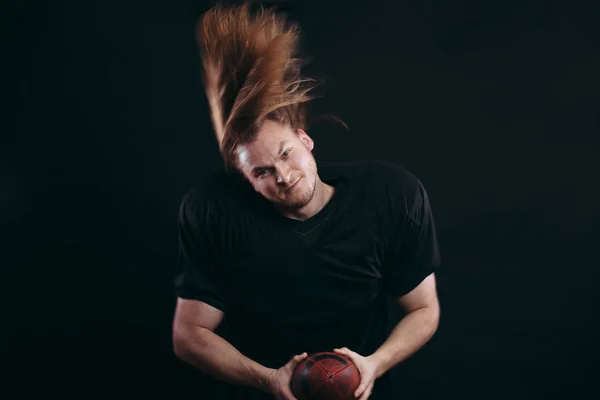 Fiducioso giocatore di football americano in abbigliamento sportivo nero con casco e palla — Foto Stock