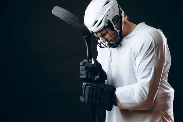 Joueur de hockey caucasien, en uniforme, isolé sur noir, prie pour la bonne chance. — Photo