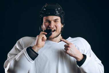 Hokey oyuncusu diski kırık dişleriyle ısırdı ve kameraya sırıtarak baktı..