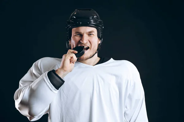 Jugador de hockey muerde el disco con los dientes rotos y mirando a la cámara con una sonrisa. —  Fotos de Stock