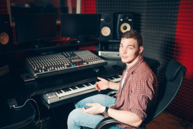 Monitör ve duvarcı önünde sandalyede oturan genç şık adam