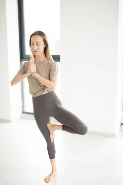 Спортивная женщина, сбалансированная в позе йоги, стоящая босиком на полу — стоковое фото