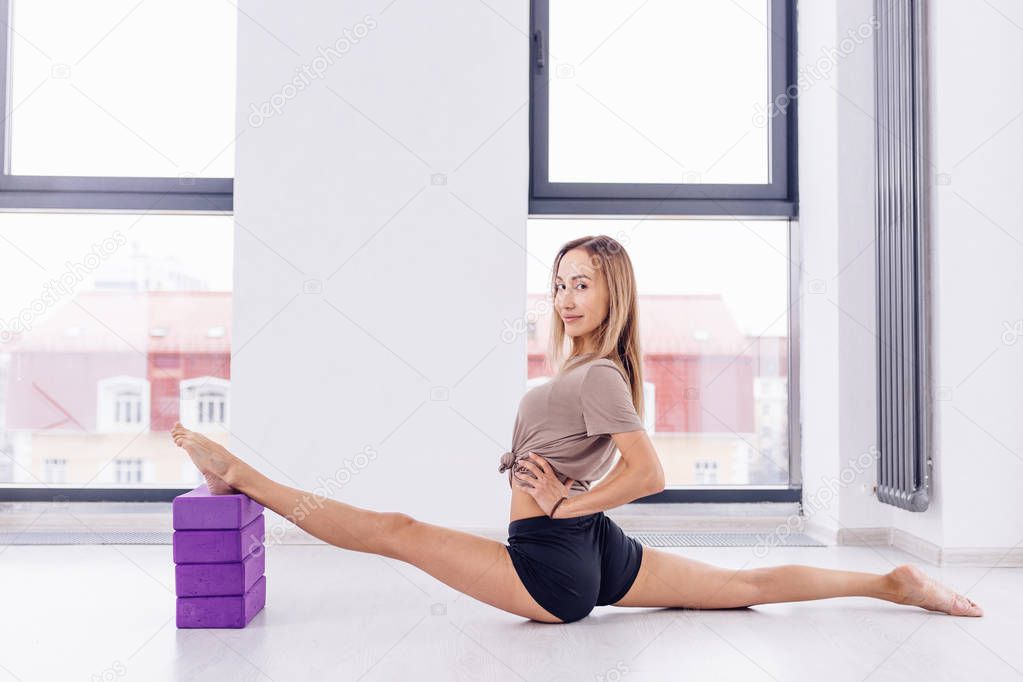 young awesome fit girl holding her legs on the pellows and doing splits