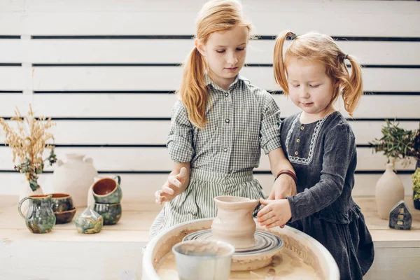 Two hardworking sweet girls making clay pot on the pottery wheel — Stock Photo, Image