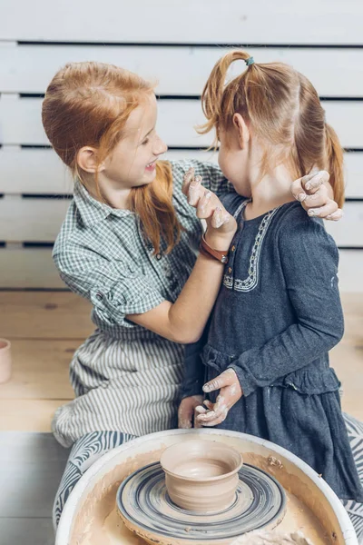 Zenzero ridere ragazza sbavatura il piccolo sorella con argilla — Foto Stock