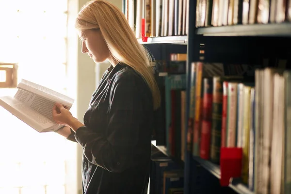 Blond lärare söka bok i biblioteket i skolan — Stockfoto