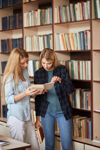 Dwóch młodych uczennic shooses książek w bibliotece — Zdjęcie stockowe