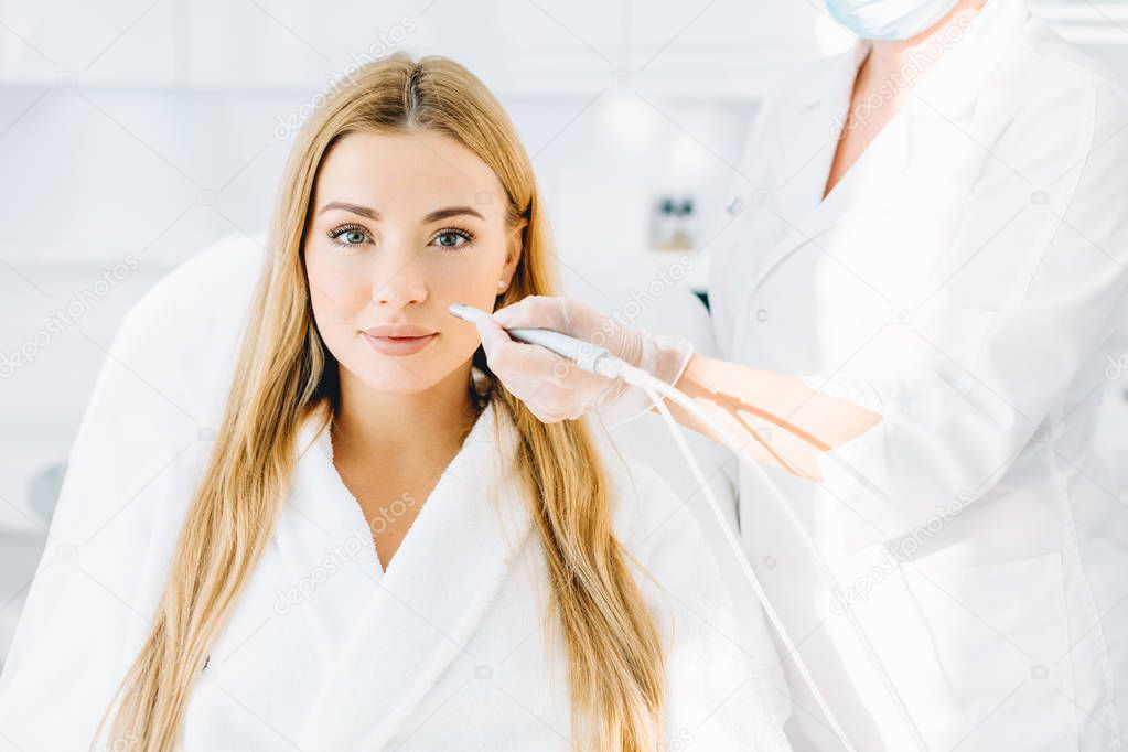Blonde woman undergoes a procedure of facial gas-liquid oxygen peeling