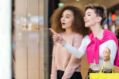 Genç bir kadın dükkanın vitrininde kocasına bir şey gösteriyor.