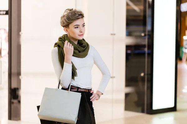 Mujer feliz con bolsas de compras en medio del centro comercial blanco borroso. —  Fotos de Stock