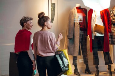 İki kadın kadınların önünde dikiz aynasından butik koleksiyonu yapıyor..