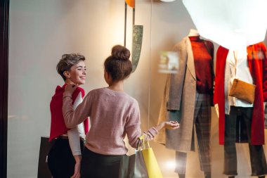İki kadın kadınların önünde dikiz aynasından butik koleksiyonu yapıyor..