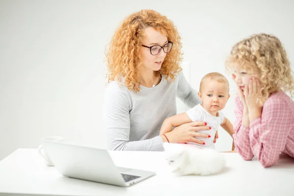 angry mother is holding interfering little baby