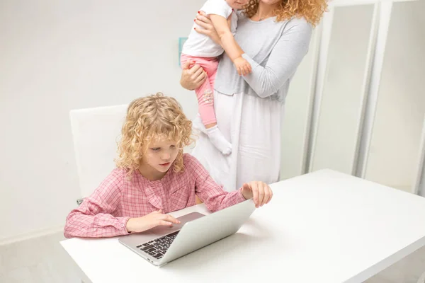 Bonita joven haciendo un proyecto para la escuela, mientras que su madre se preocupa por la hermana pequeña —  Fotos de Stock