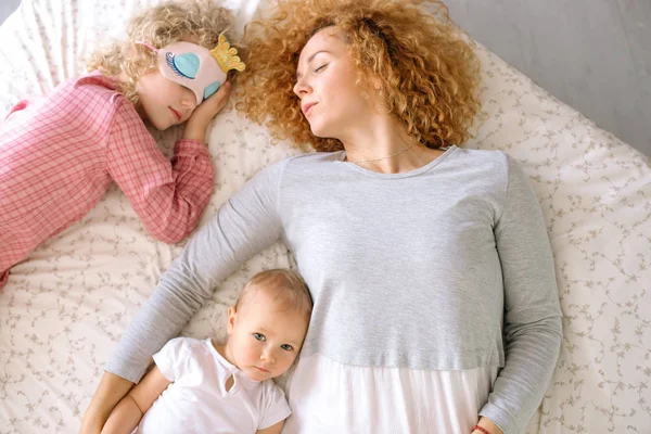 Asszony és lánya a többi gyakorol az ágy, míg a baba már felébred — Stock Fotó