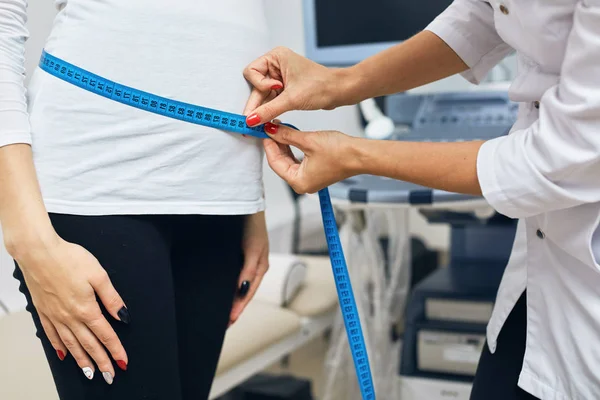 Terapeuta es medir el estómago de una mujer que lleva un bebé —  Fotos de Stock