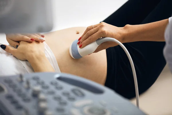 Лікар тримає ультразвуковий пристрій на животі вагітної дівчини — стокове фото