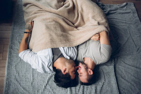 Schöner schläfriger Mann mit Borsten küsst gute Nacht männlicher Partner im Bett liegend — Stockfoto