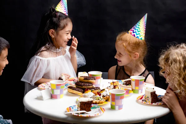 Niños pequeños y felices divirtiéndose con pastel durante la fiesta —  Fotos de Stock