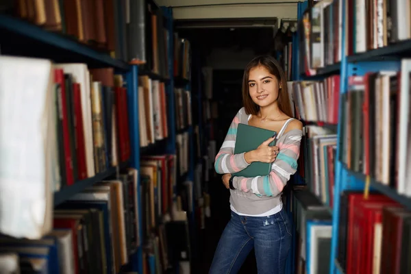 Blonde teacher searching book in the library in school