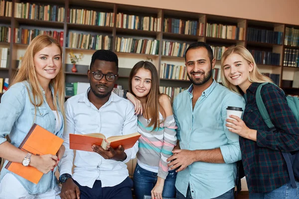 Estudantes multirraciais se divertindo na biblioteca enquanto se preparam para exames . — Fotografia de Stock