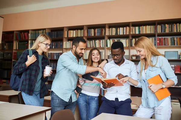 Estudiantes multirraciales se divierten en la biblioteca mientras se preparan para los exámenes . — Foto de Stock