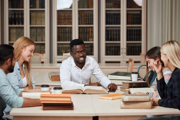 Skupina mnohonárodnostní lidí, studiu knih v knihovně školy. — Stock fotografie