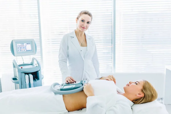 Young woman lying in medical couch with cooling elements on belly in clinic