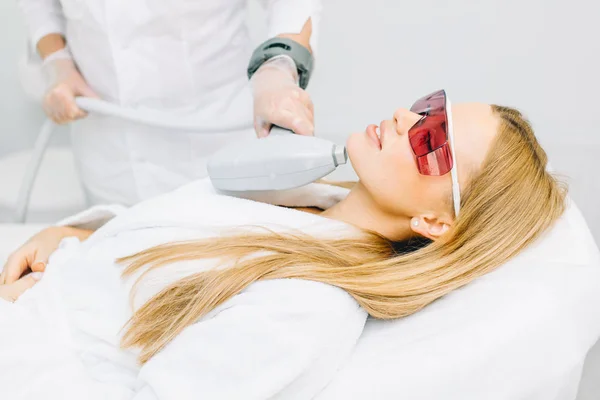 Woman getting laser and ultrasound face treatment in medical spa center