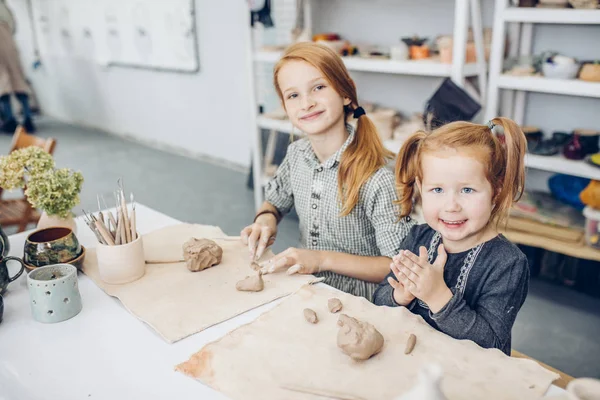 Приятные дети сидят за столом и учатся делать сувениры — стоковое фото