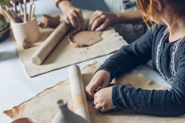 Primer plano de los niños lindos haciendo una arcilla marrón rodante — Foto de Stock